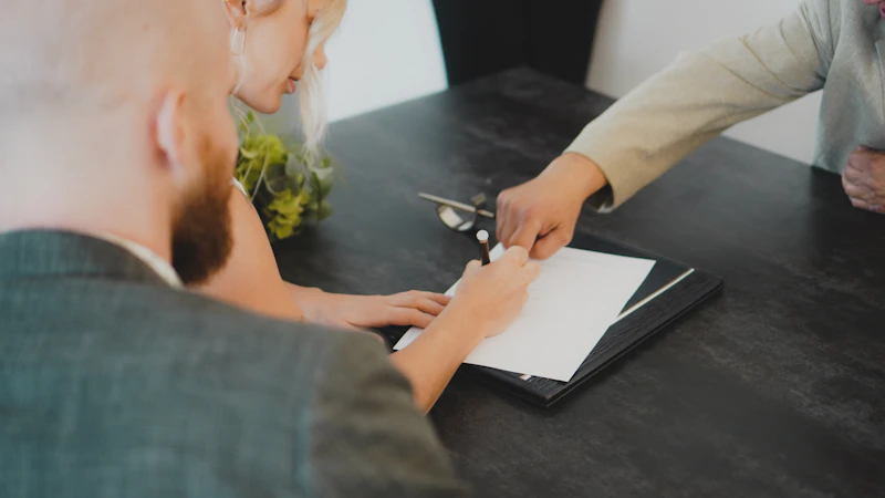 A couple signing a document together at a desk