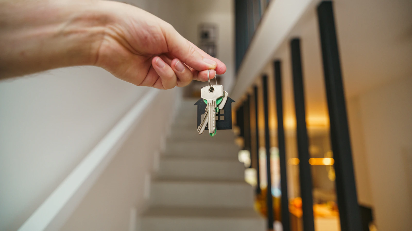 A hand holding keys with a house keychain