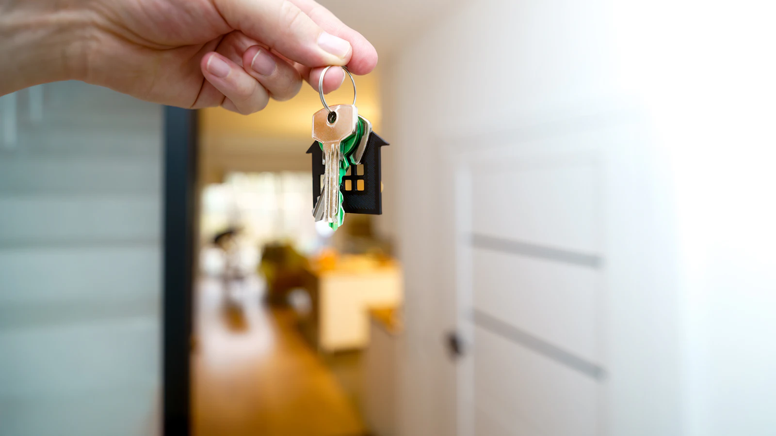 A person holding house keys in front of a front door