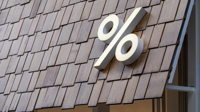 A large white percentage sign standing on a wooden roof