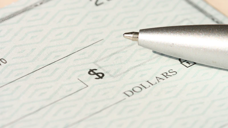A pen resting on a check near the dollars line