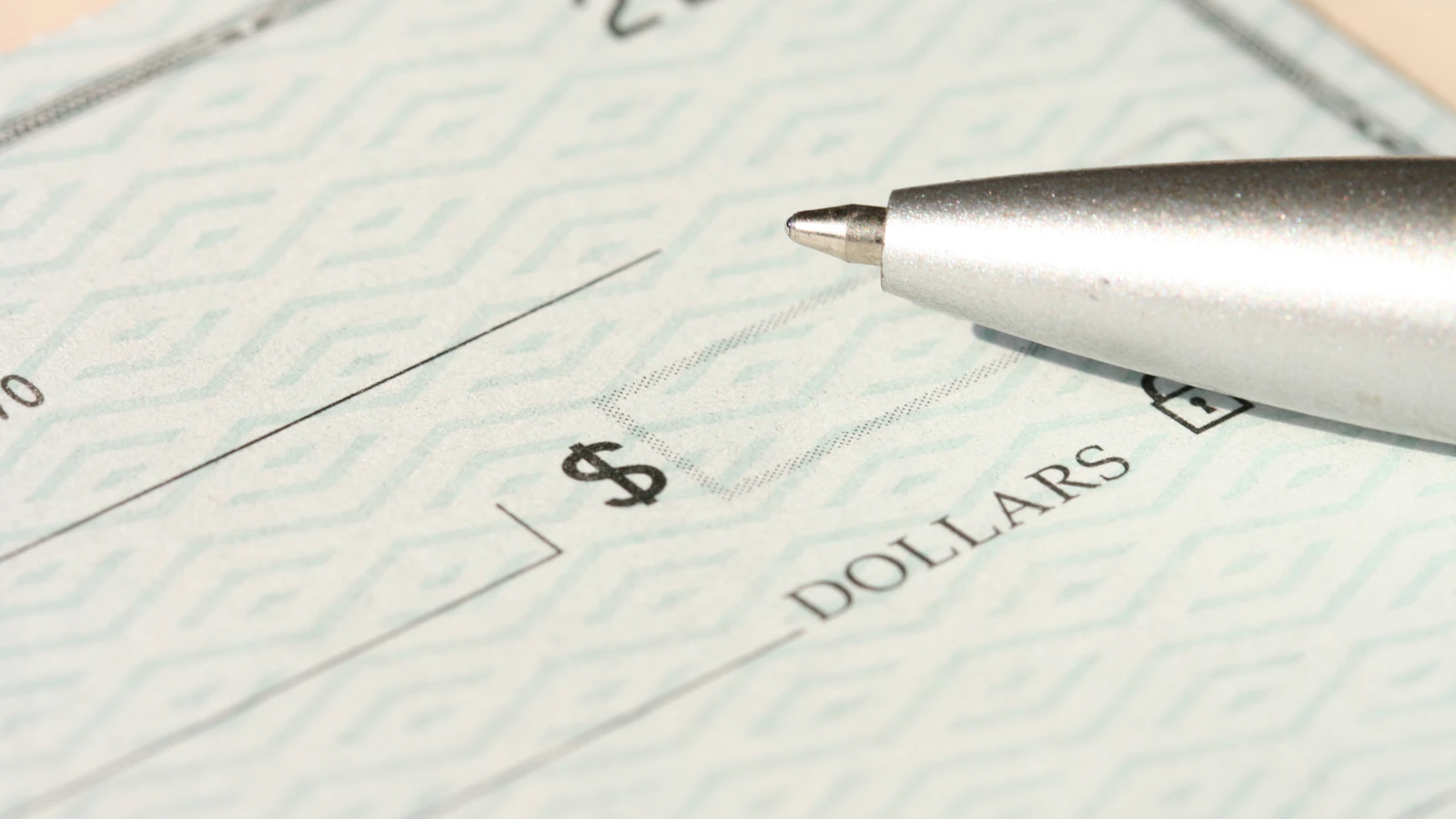 A pen resting on a check near the dollars line