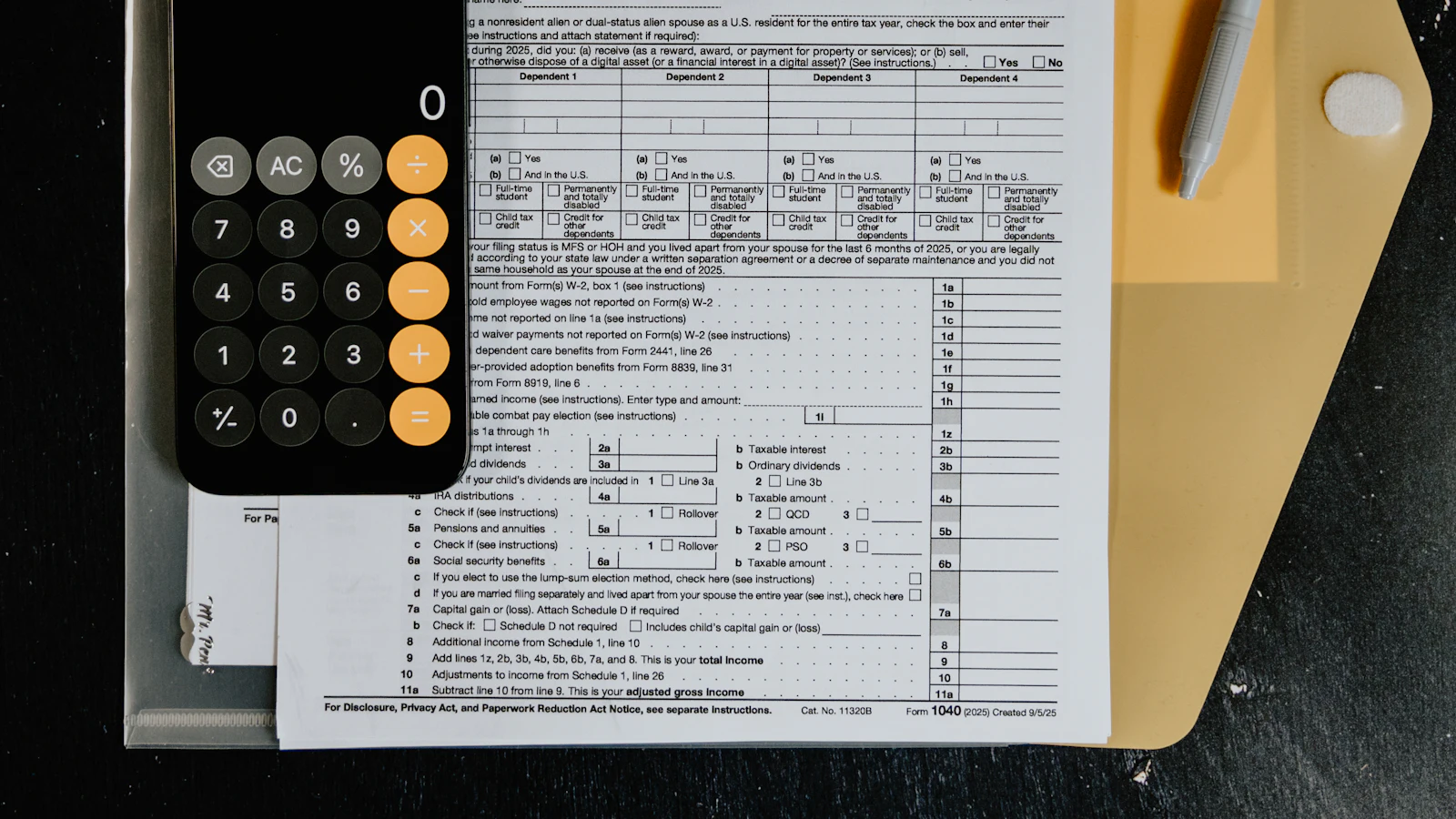Tax forms with a calculator and pen laid out on a desk