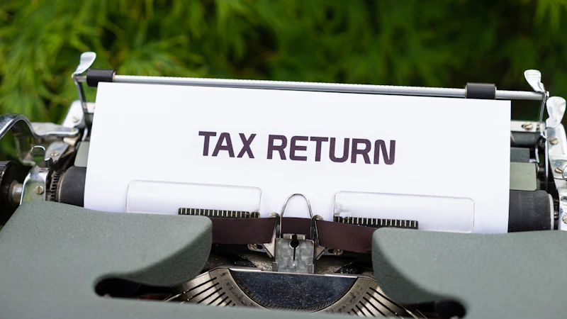 A typewriter with a sheet of paper reading tax return