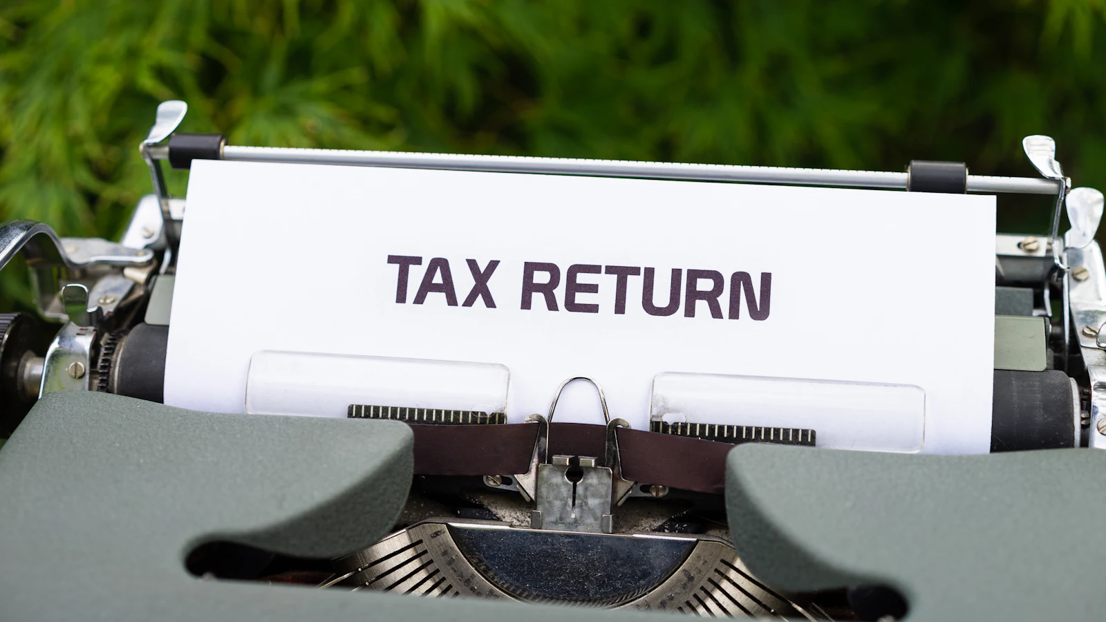 A typewriter with a sheet of paper reading tax return